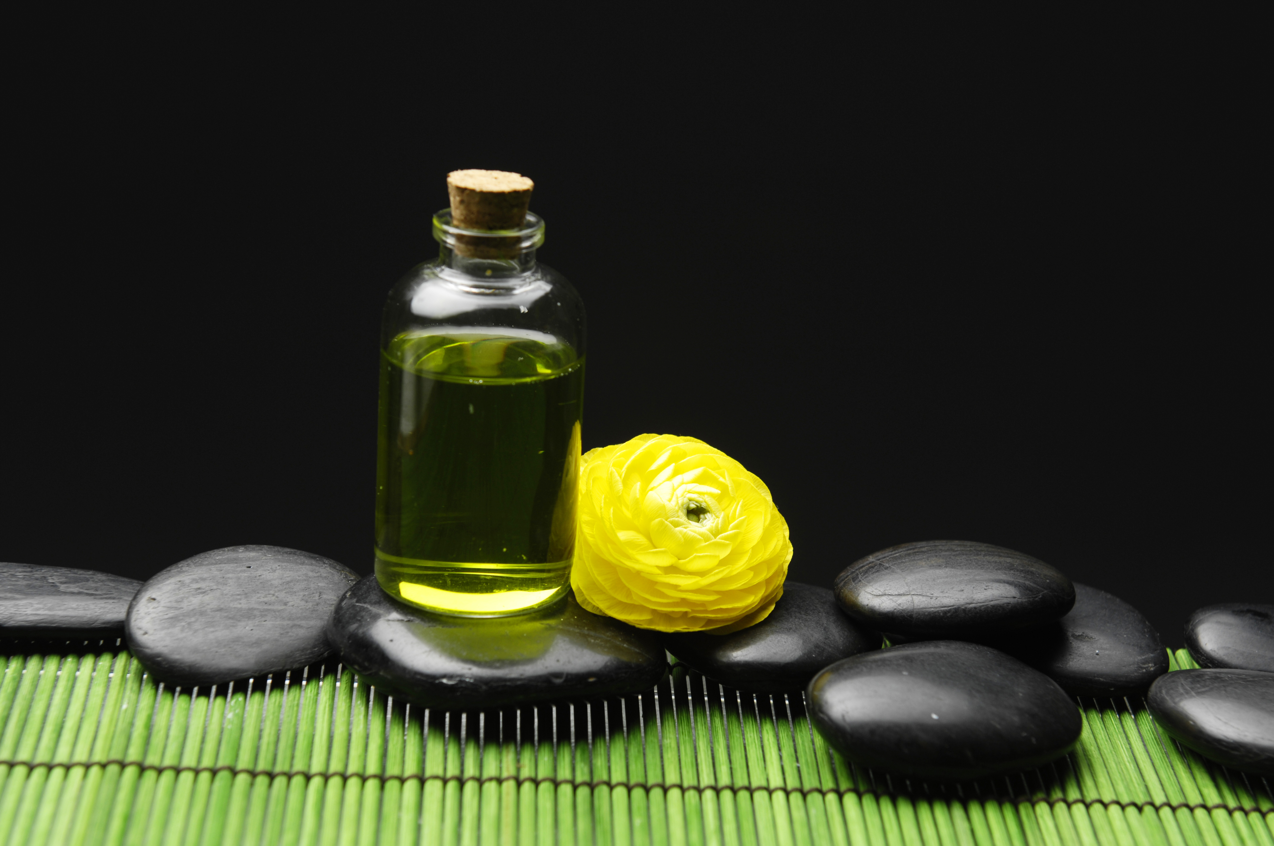 flowers and spa rocks on a table with a beautiful glass jar with cbd oil 