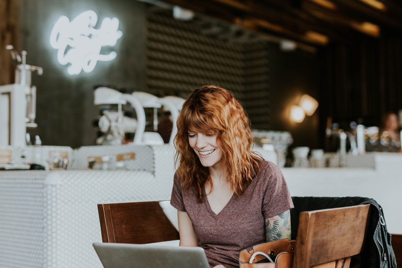 Portrait of young redhead worker sitting in coworking space. Female freelancer using a laptop computer working on her CBD business.