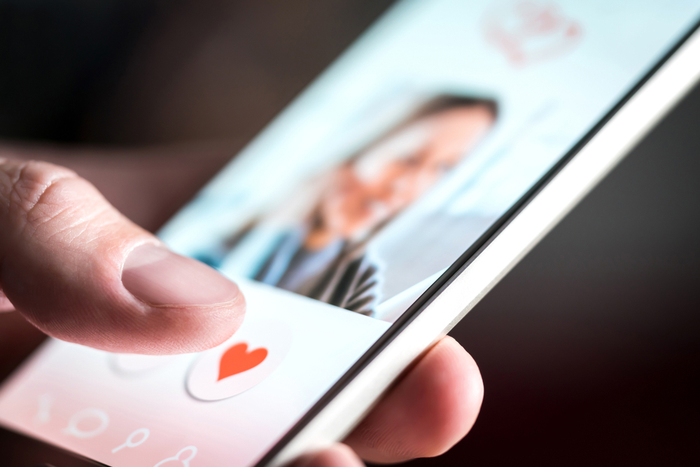 Close up of a man flipping through profiles on a relationship site or app