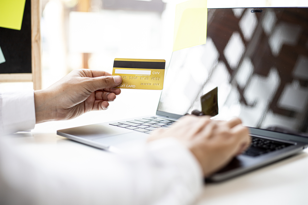 Businessman hand holding credit card to online shopping with laptop to represent  Merchant Account