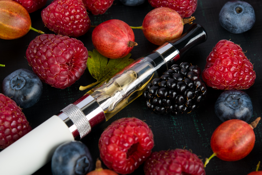 vape pen laying around different kind of berries to show Ecig Merchant Accounts