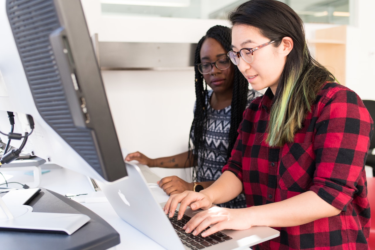 Young women in office working together on desktop to represent Help Desk Merchant Accounts