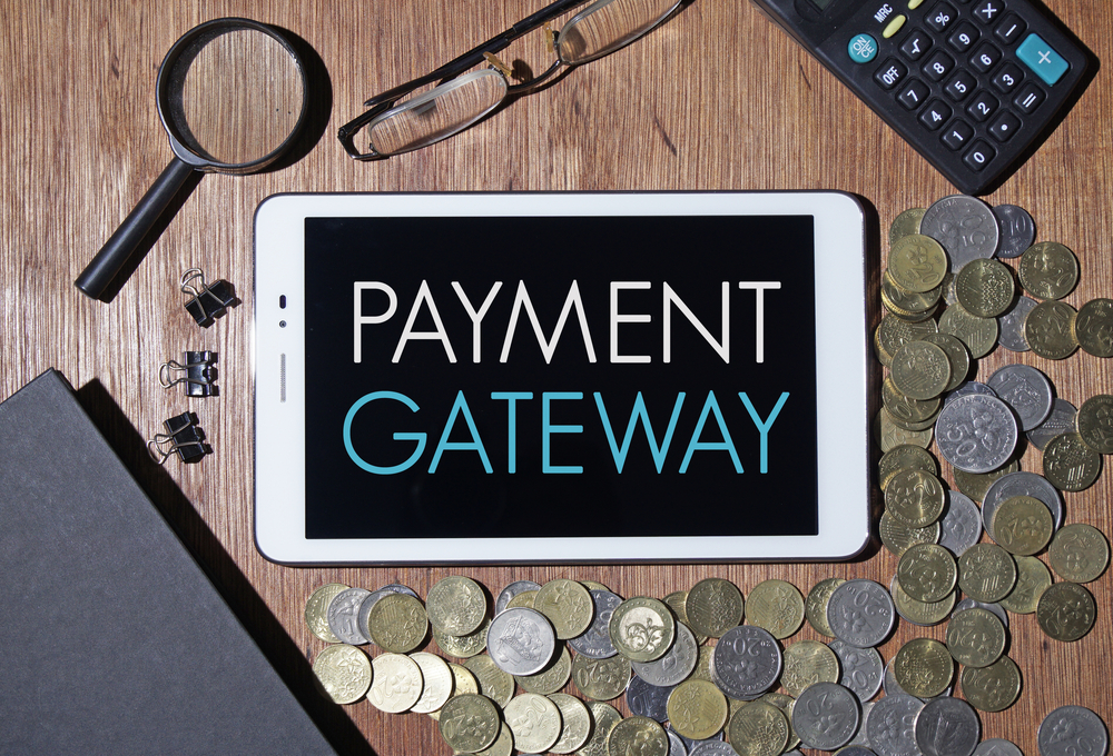 the payment gateway on a tablet with money and office gadgets around to symbolized Merchant Account vs Payment Gateway