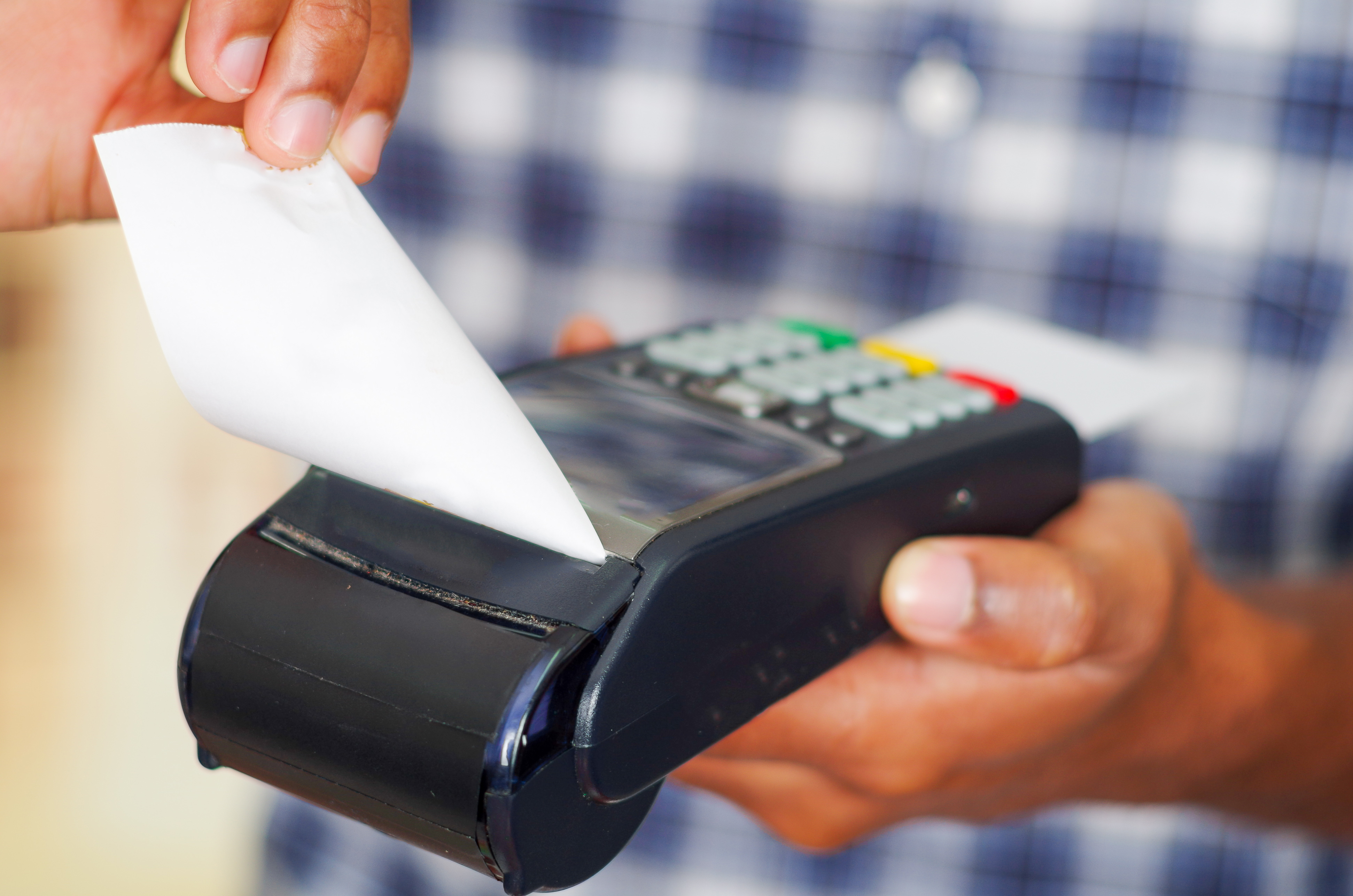 Close-up look of a man with a payment terminal while holding a receipt for completing a purchase to symbolized online merchant account