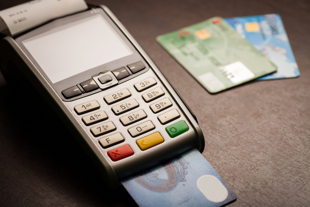 Credit card with payment terminal on wooden desk to represent High-Risk Merchants