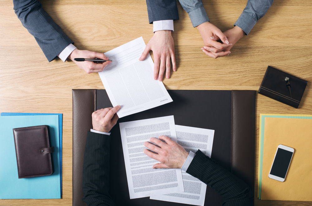 top view of a meeting while they sign business papers to symbolized High-Risk Transactions