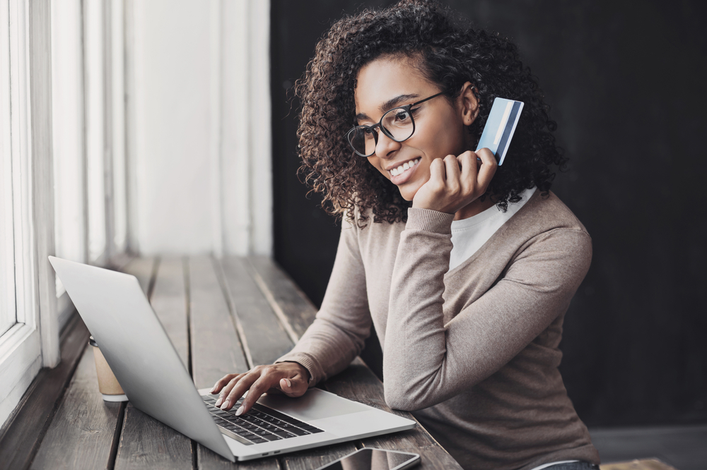 Young woman holding credit card and using laptop computer. Online shopping, Payment Processing Merchant Account