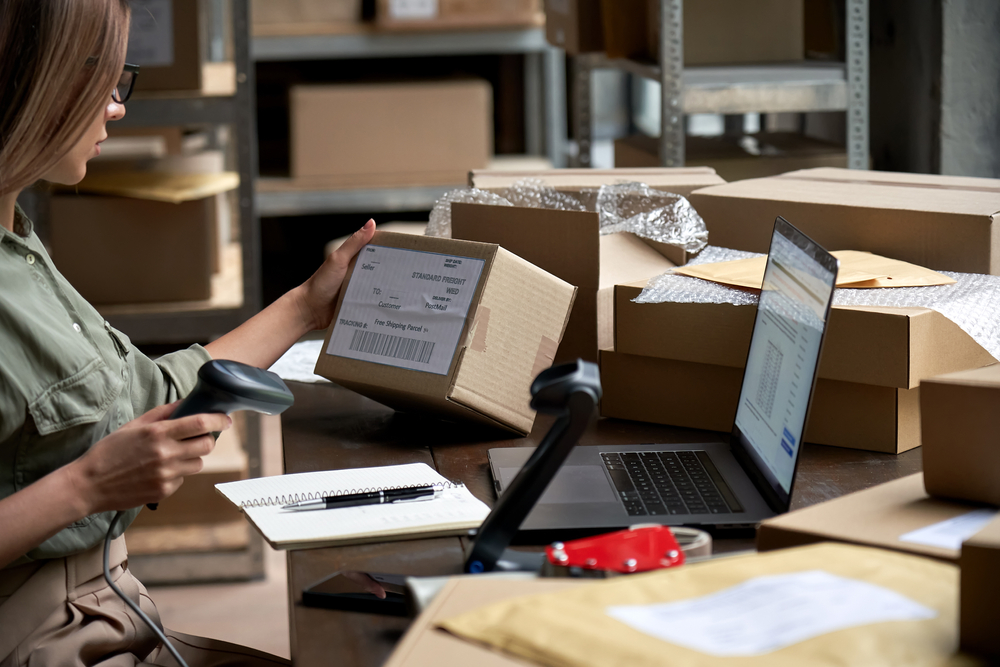 A business owner scanning a package in a warehouse and utilizing her bad credit merchant account.