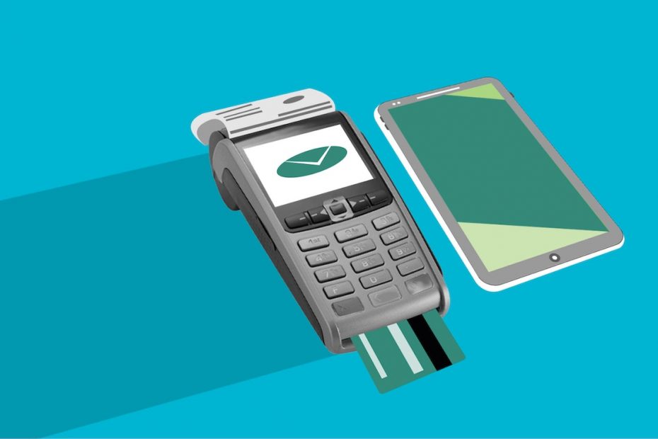 A card in a payment kiosk with a green check on the screen when the payment goes through a payment processing service and a mobile phone beside it.
