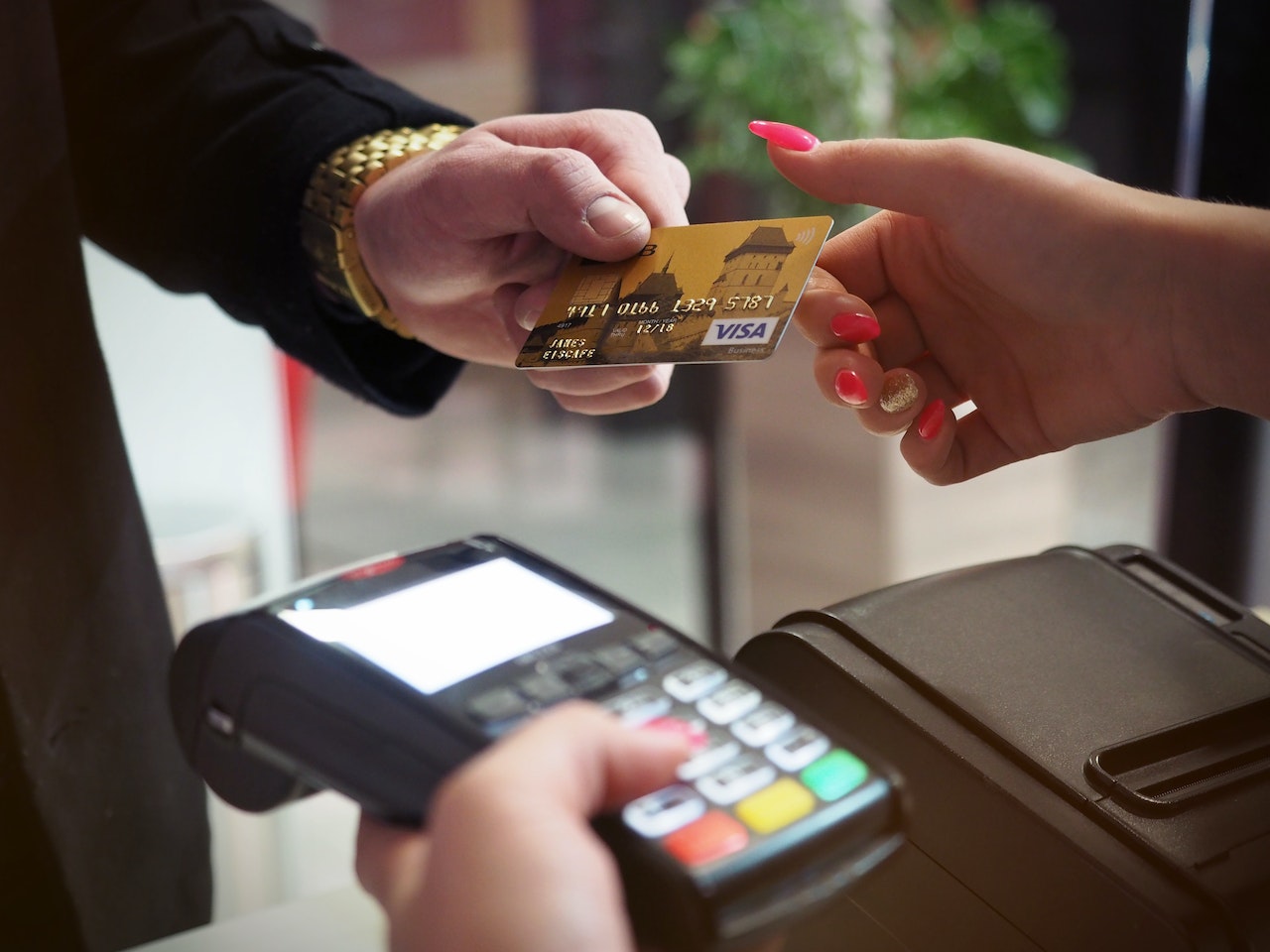 A male customer holding a credit card near NFC terminal makes a contactless payment to Gateway Processing