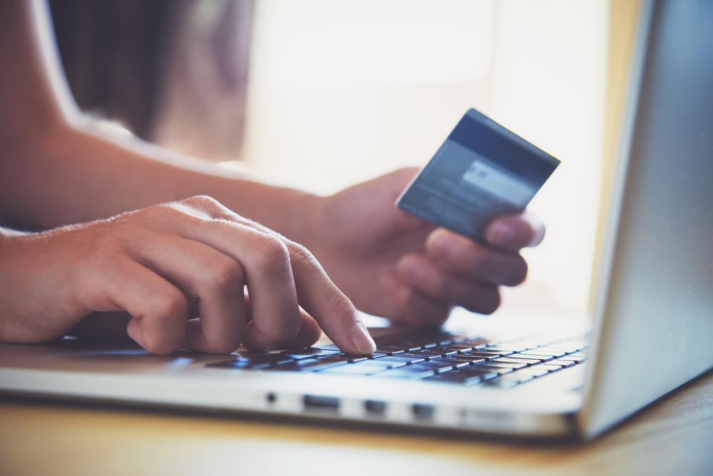 Close-up look of woman's hands using her credit card in front of a laptop