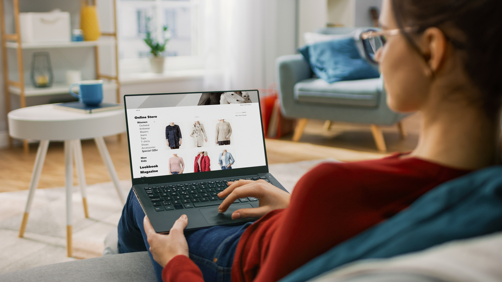 Female Shopping Concept. Back view of woman browsing online, clothing stores, using modern laptop to symbolizing High-Risk Business Payment Gateways