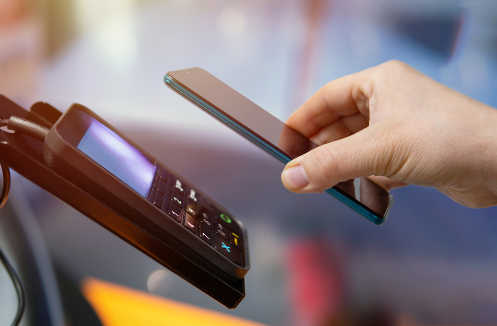 Customer paying bill through smartphone using NFC technology.Closeup of hand making payment through contactless machine.: Small Business Payment Processing