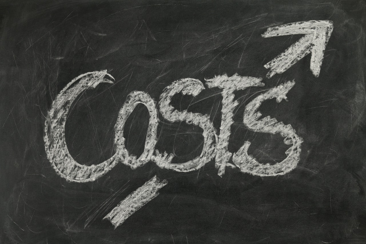 The word costs with an arrow pointing up written on a chalkboard referencing the costs involved with card purchases.