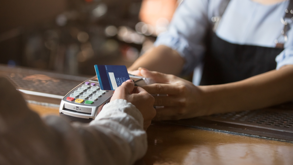 Contactless payment concept, female customer holding credit card near nfc technology on counter: Small Business Payment Processing