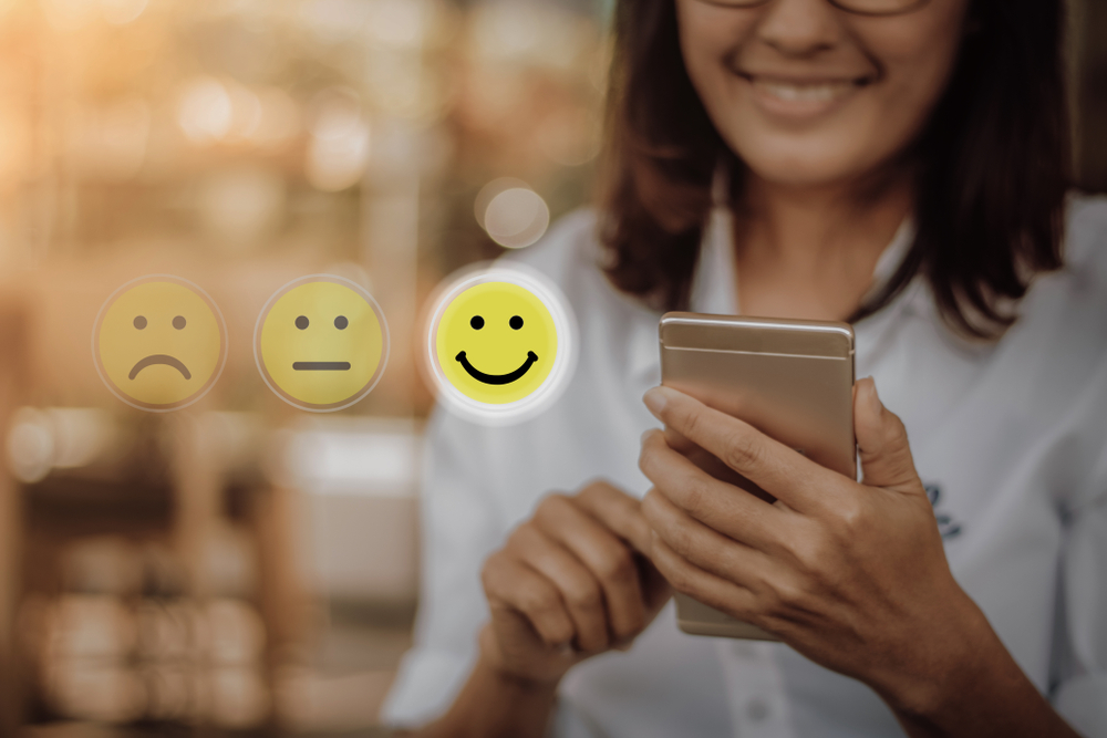 women giving customer feedback on mobile phone based on smiles icons for Payment Gateway