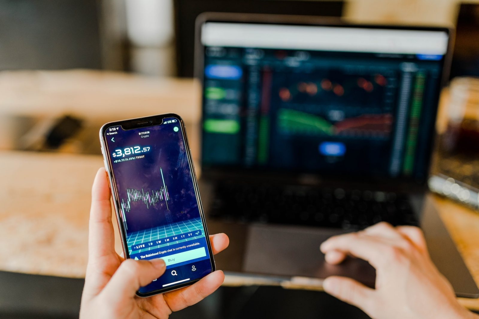 stockbroker using phone and laptop for profit gain analysis workplace. Man holding phone with graph price to represent Electronic Payment Process