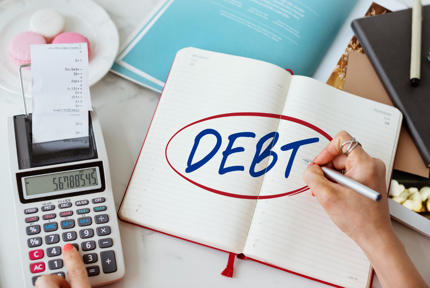 bussines woman with a calculator and notepad with the word debt written and circled in the middle for Collection Agency Merchant Services