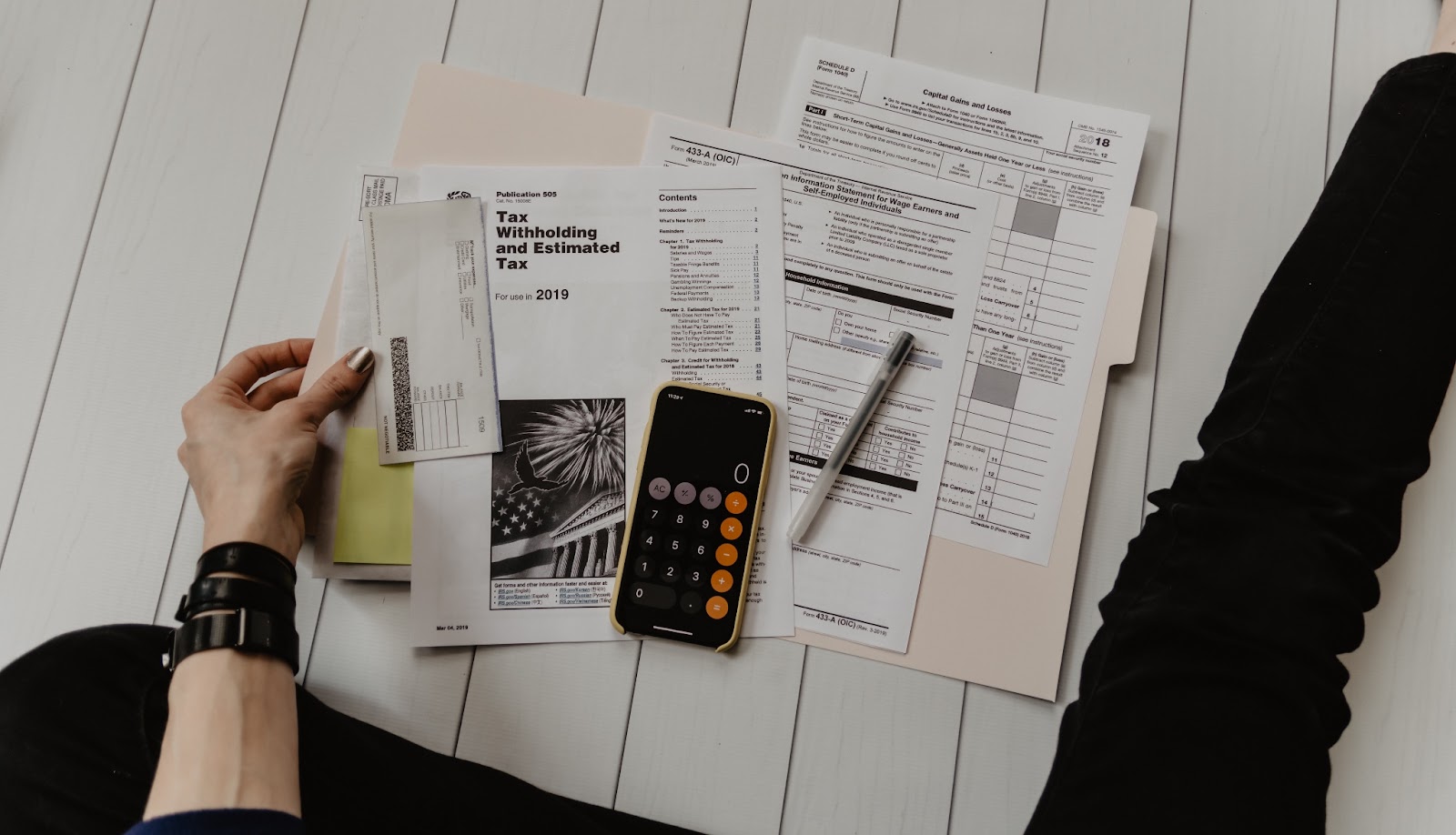 Person sitting on floor with checkbook and papers sprawled out to symbolize check payment processing
