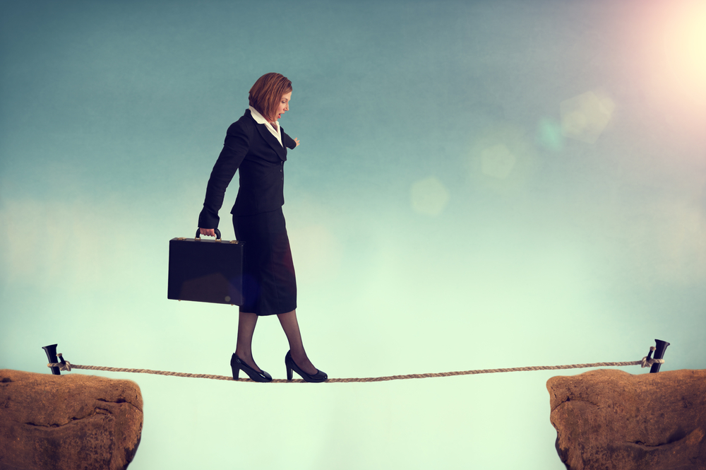 A businesswoman with a briefcase walking on a tightrope symbolizes a high-risk business.
