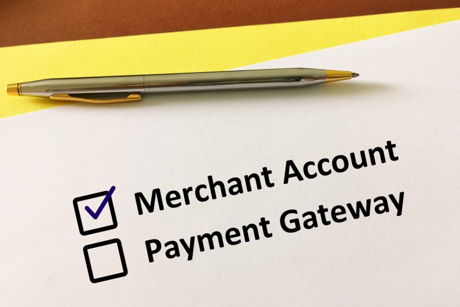 The words merchant account and payment gateway are written on a piece of paper with boxes beside them, and the box for the merchant account is checked.