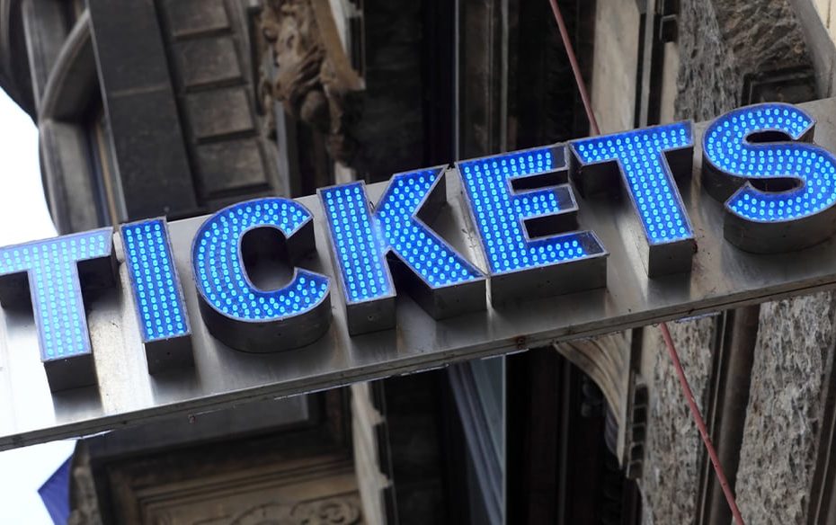 A building with a blue neon sign spelling out the word tickets.