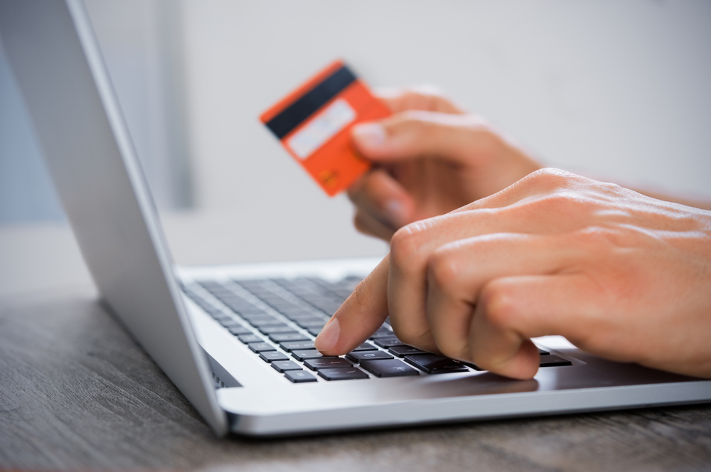 A person making a payment on a laptop with a card for an online dating service.