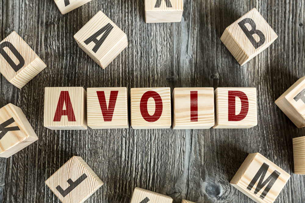 Wooden blocks spelling out the word avoid being surrounded by other random lettered blocks.