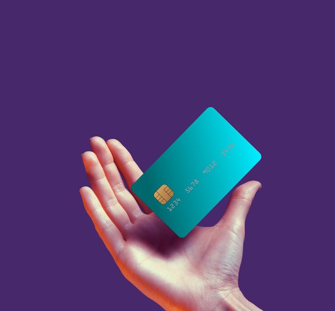 A person's hand holding a credit card to make payment.