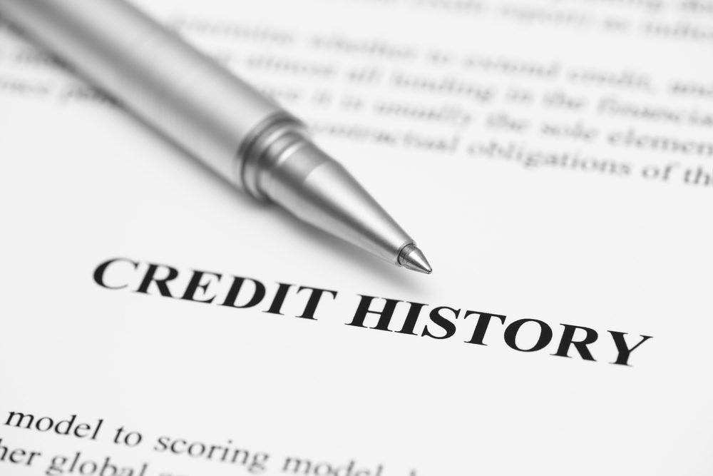 A piece of paper with the word credit history and a gray pen pointing toward it.
