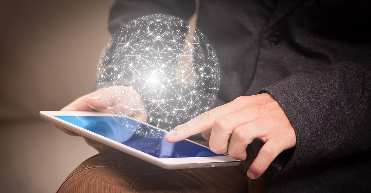 A person using a tablet with a globe emanating from the laptop. 