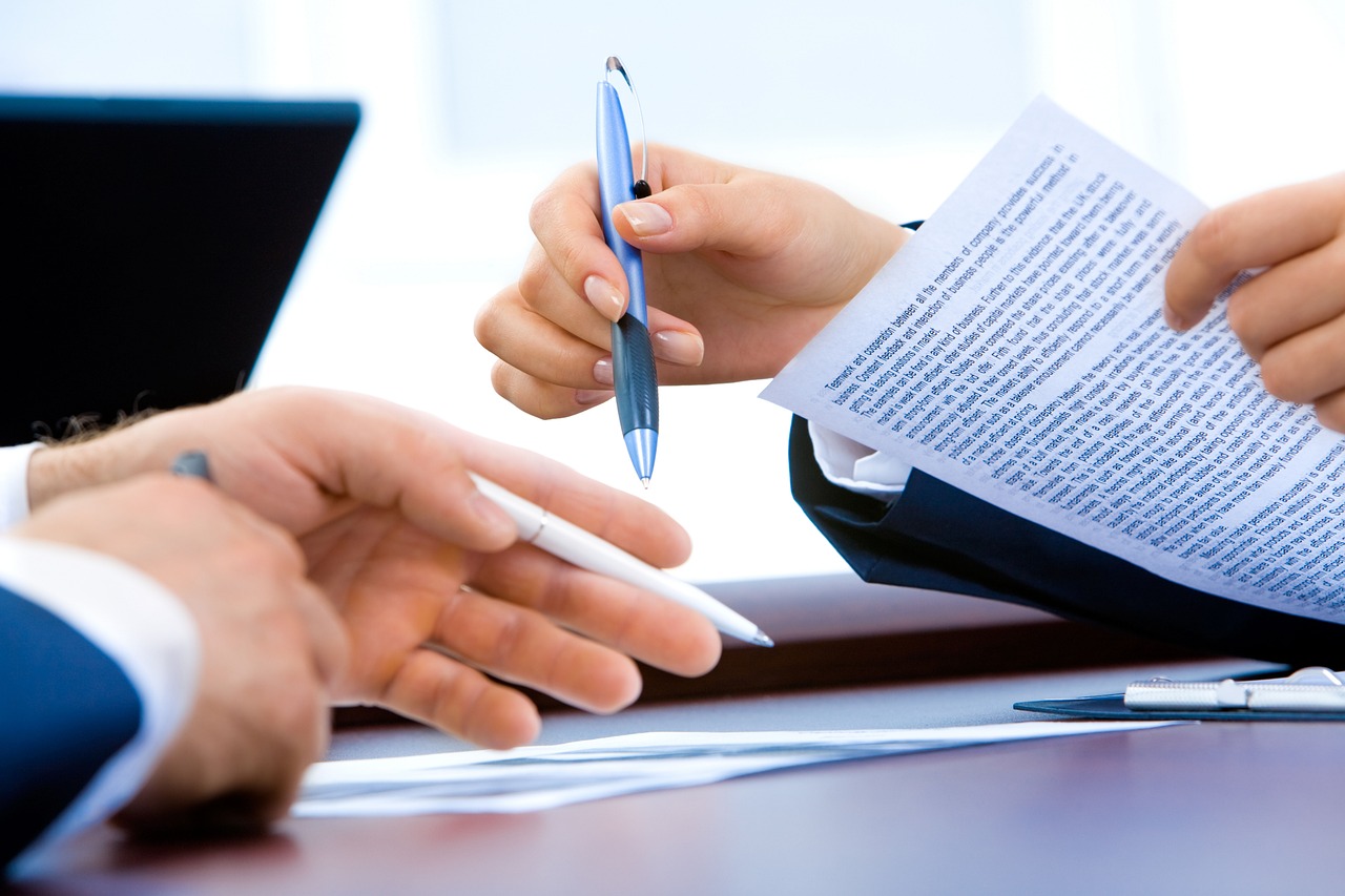 The hands of office workers reviewing a contract. 