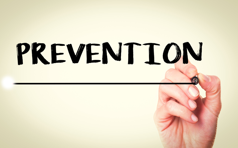 A person writing and underlining the word prevention.