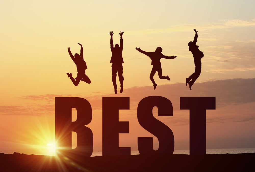 The word best with happy people jumping off of it and into the air with a sunset in the background.