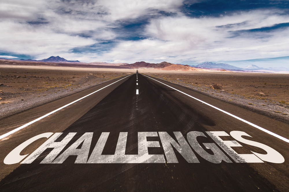 The word challenges is painted on a desert road.