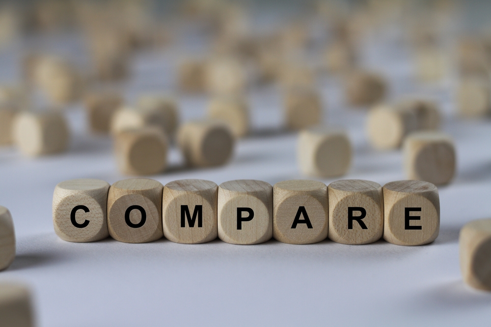 Wooden blocks spelling out the word compare surrounded by other wooden blocks in the background.