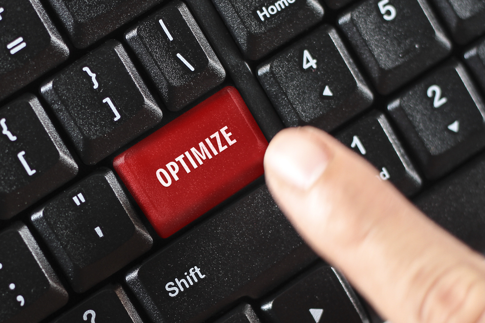  A red key on a keyboard with the word optimize on it and a person/s finger about to click it.
